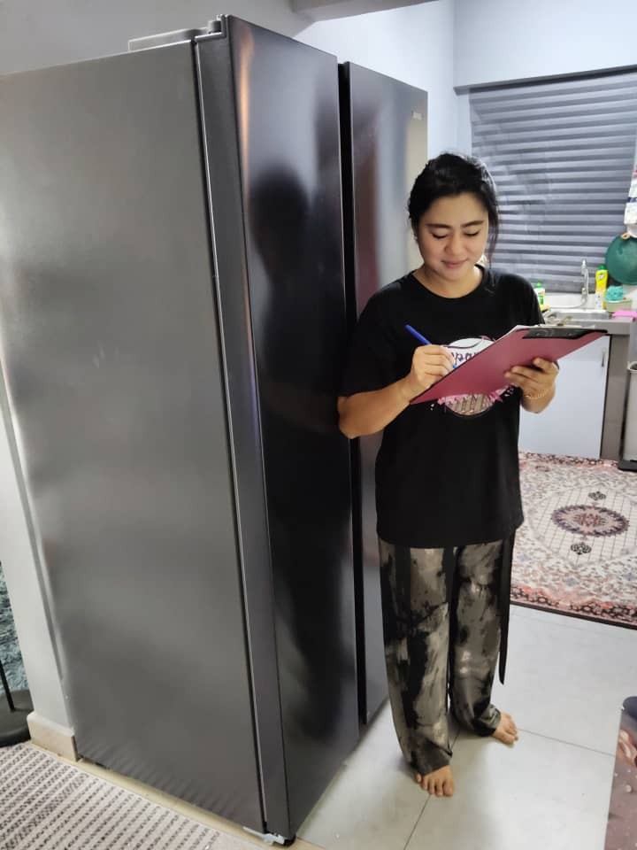 Pelanggan menandatangani borang penerimaan di sebelah peti sejuk side-by-side