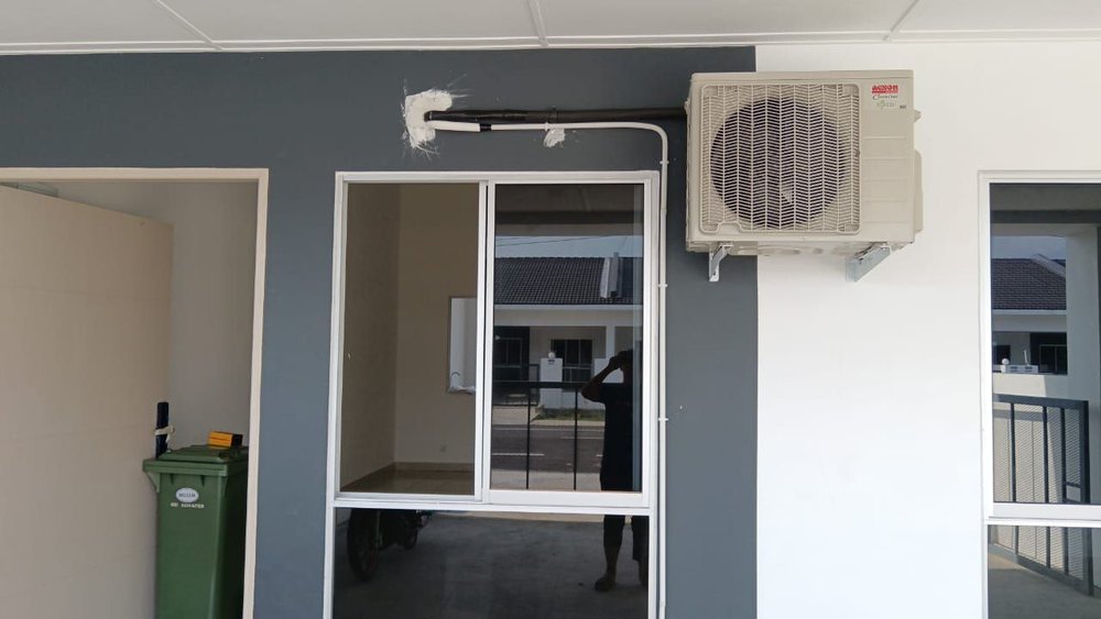 Unit luaran aircond Acson dengan paip yang kemas di dinding rumah