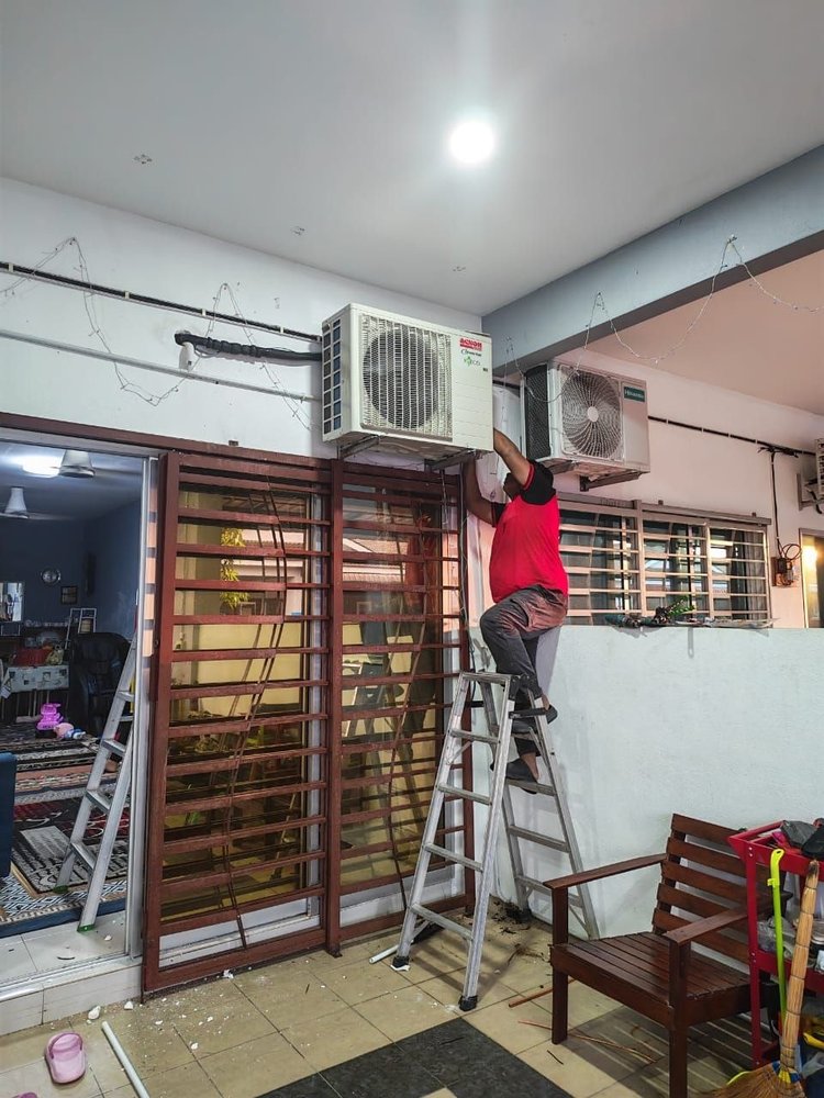 Juruteknik memasang unit luaran aircond Acson di luar rumah