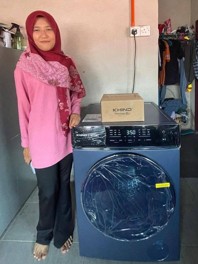 Pelanggan tersenyum di sebelah washer dryer Khind yang baru dipasang